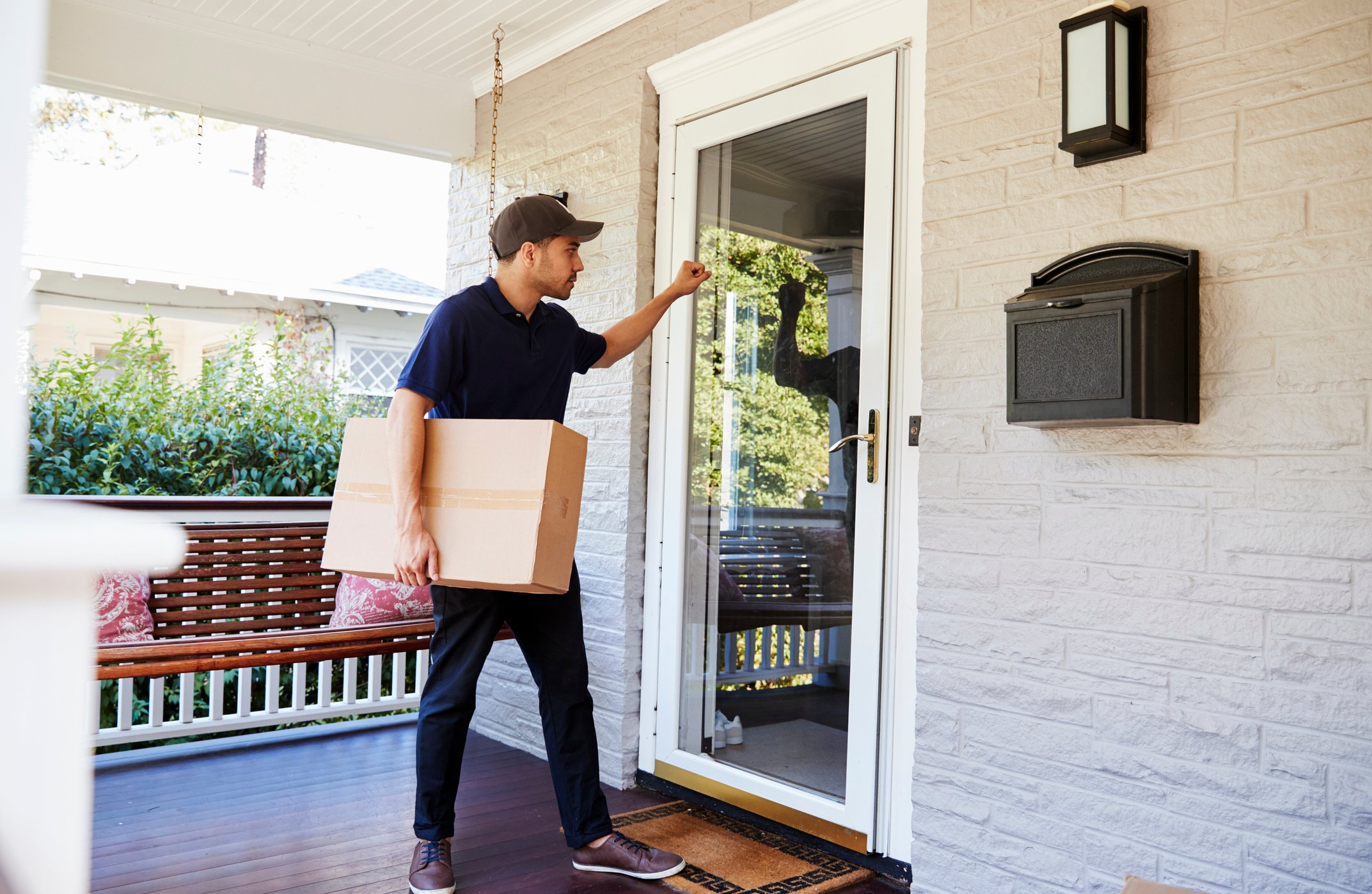 A deliveryman knocking on a door with a package.