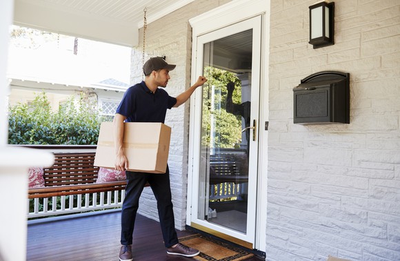 A deliveryman knocking on a door with a package.