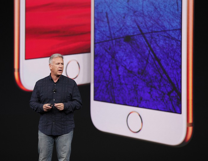 Apple executive Phil Schiller on stage with images of the iPhone 8 and iPhone 8 Plus projected behind him.