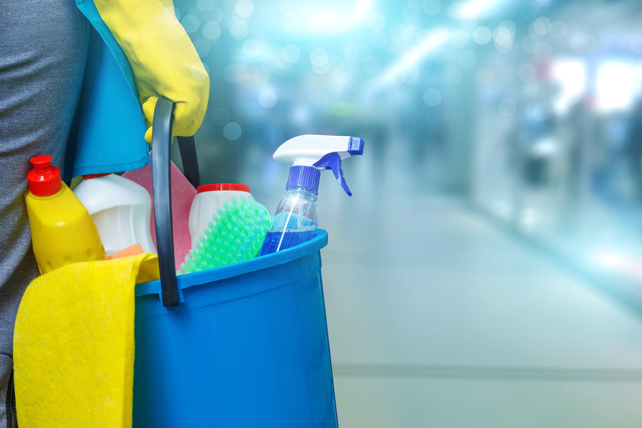 A cleaning person holds a bucket of cleaning products.