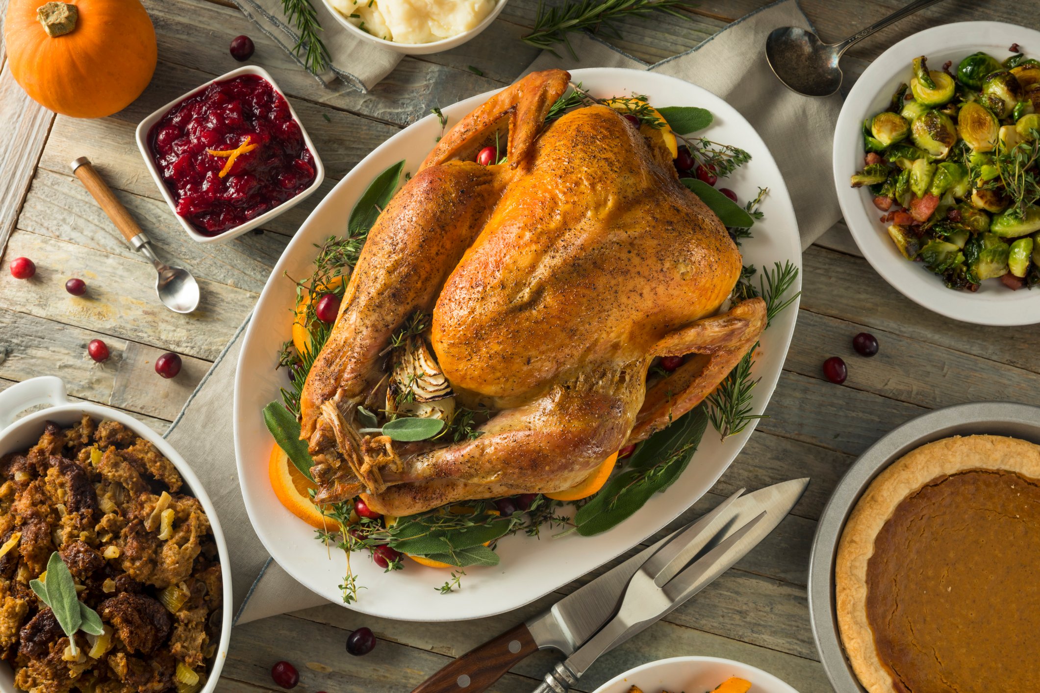 Large cooked turkey surrounded by side dishes.