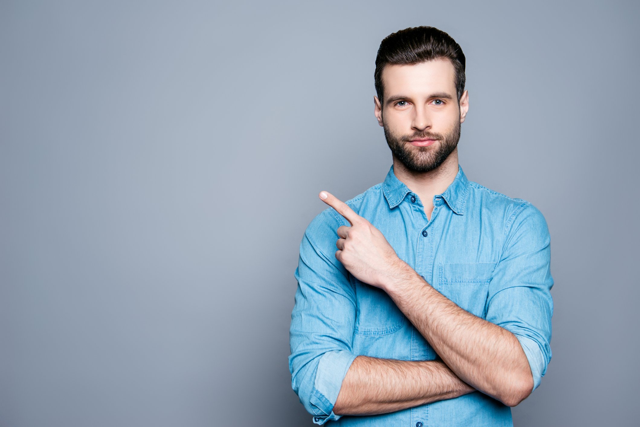 Confident man making pointing motion against a gray background