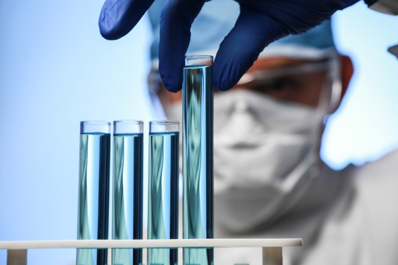 Scientist holding a test tube next to three other test tubes 