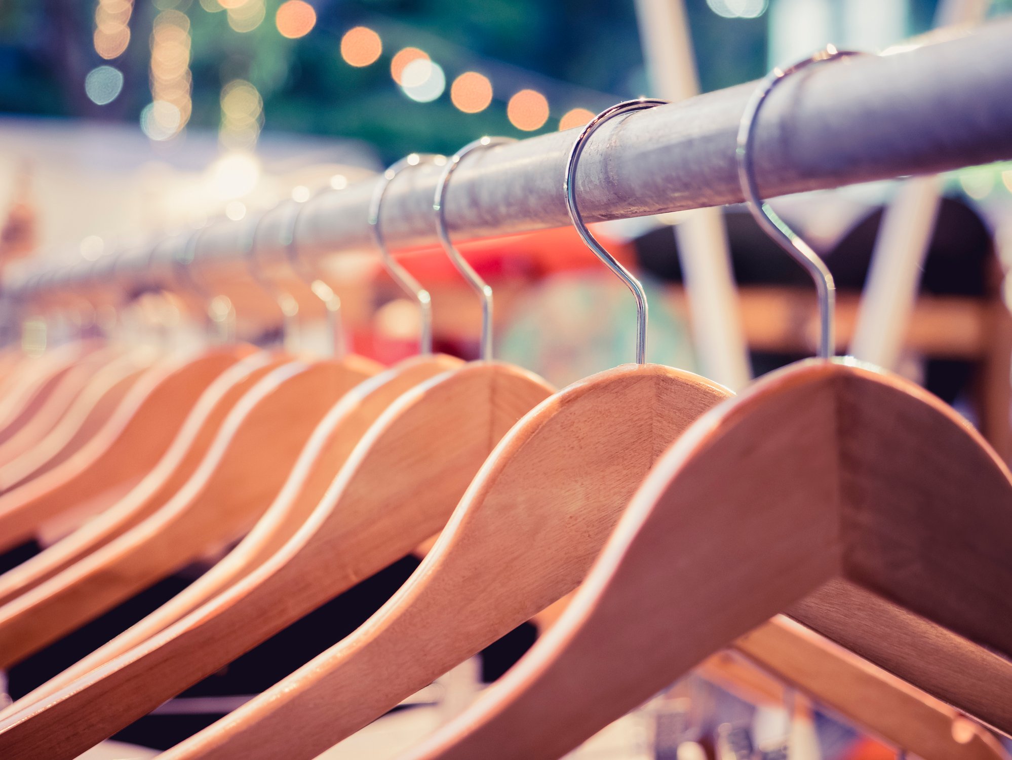Wooden hangers on a retail fashion shopping rack.