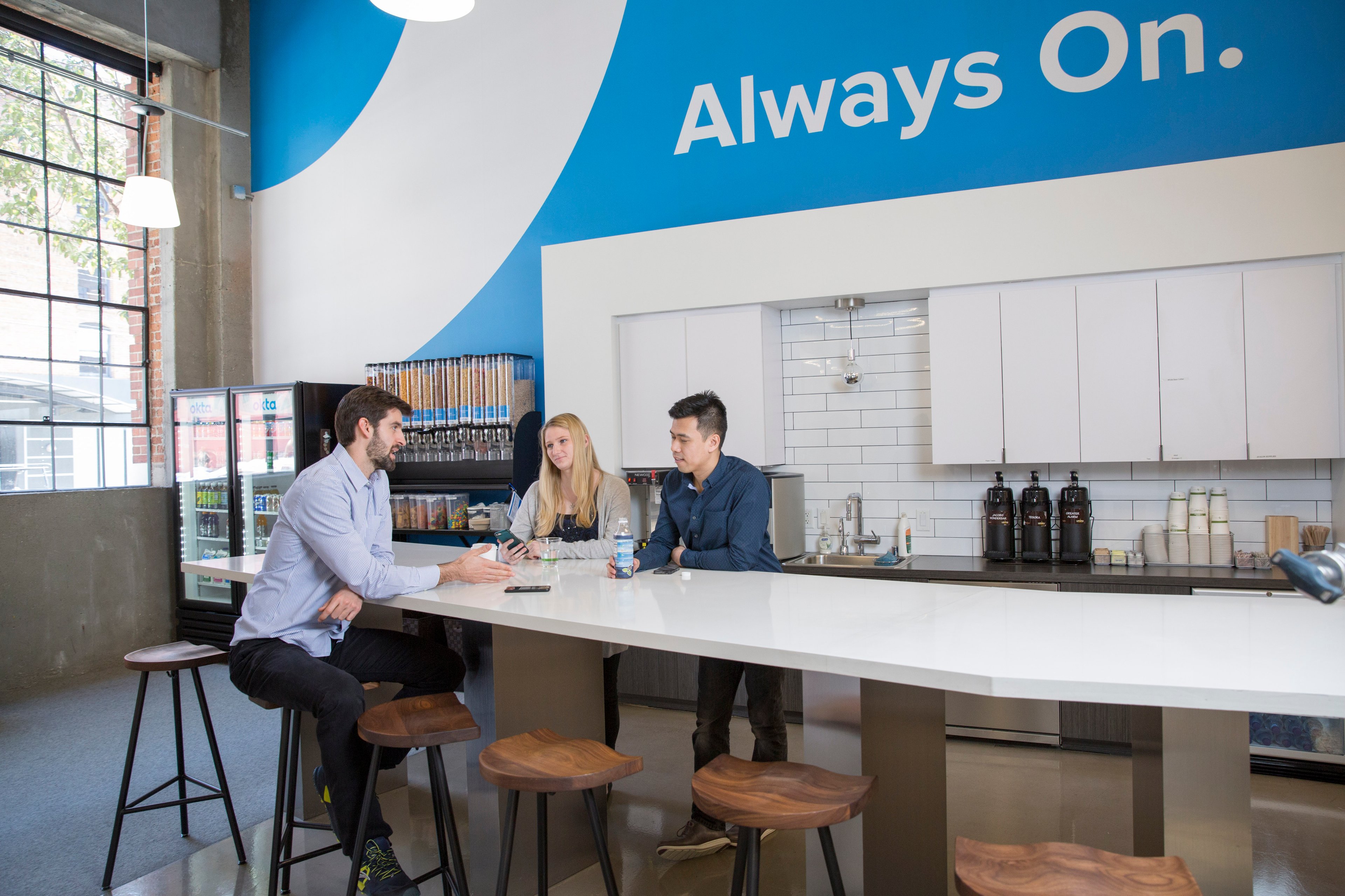 Three employees in the Okta break room.