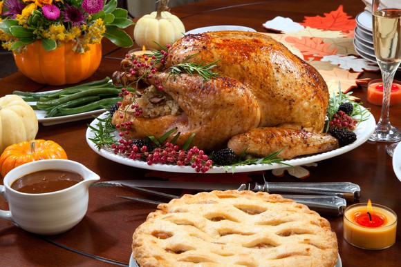 A roasted turkey surrounded by other food dishes and fall decorations.