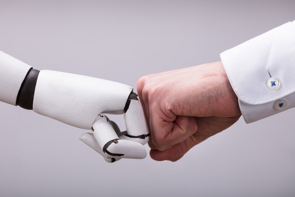 A robot and a human hand bumping fists.