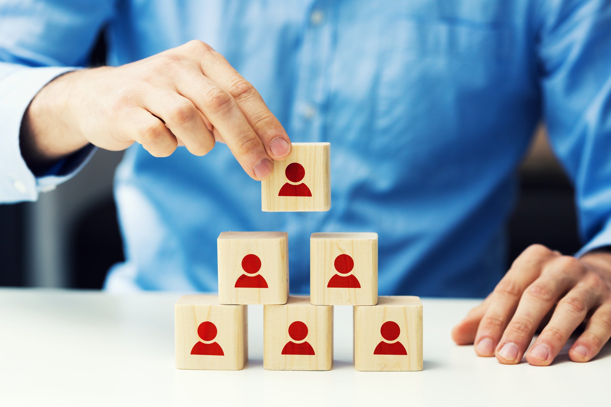 A person stacks blocks representing people.