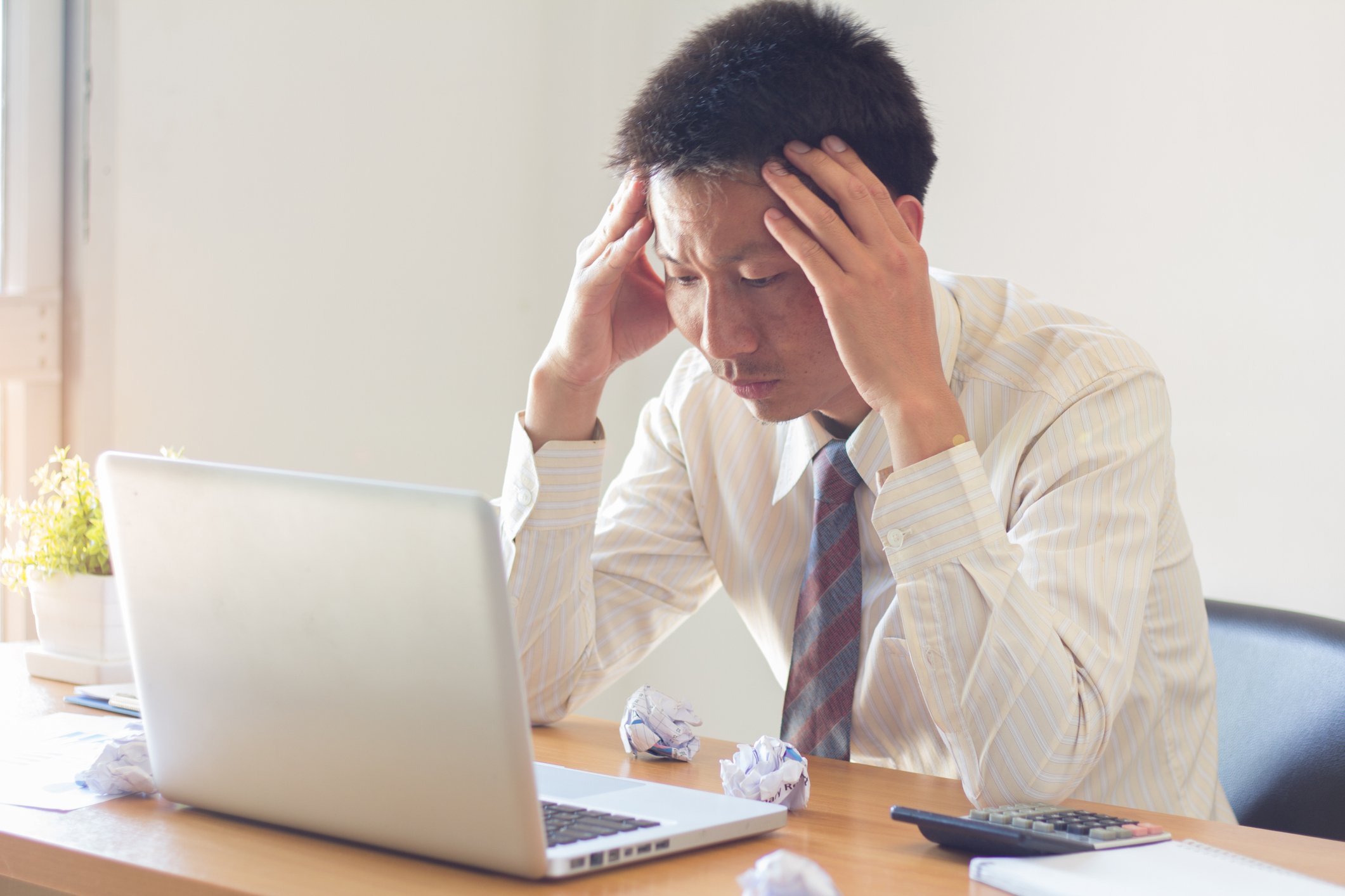 Man at laptop holding head as if tired