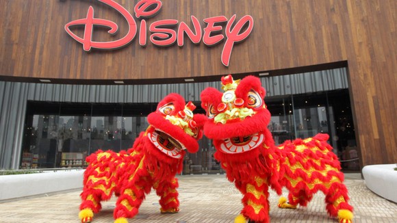 Two Chinese dragons in front of a Disney sign at a park.