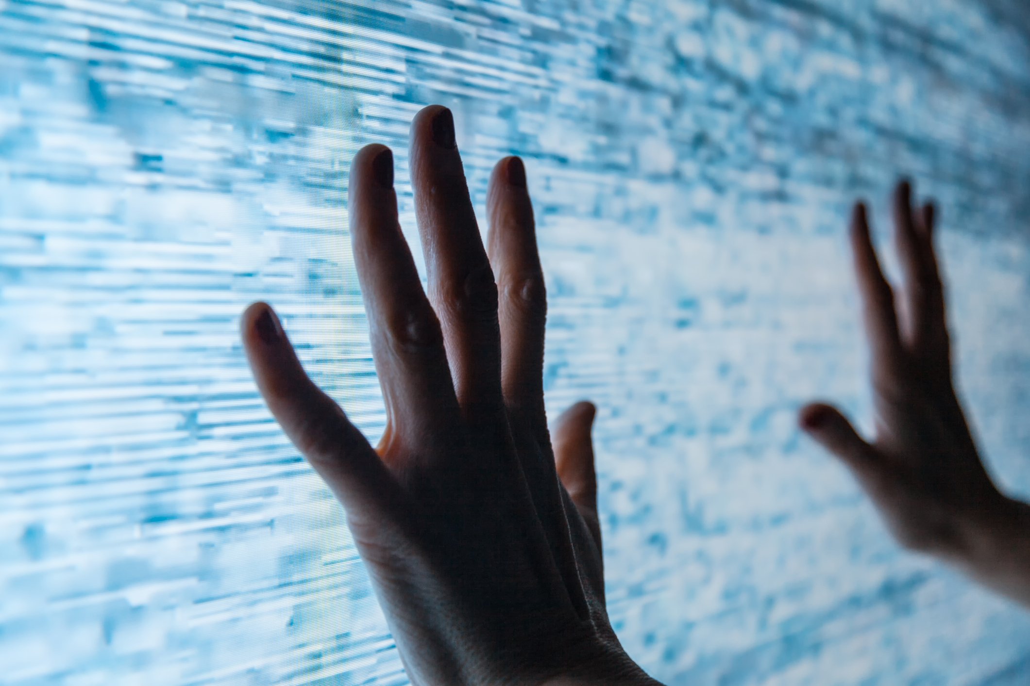 Two hands reach out to touch a large TV screen with a poor signal.
