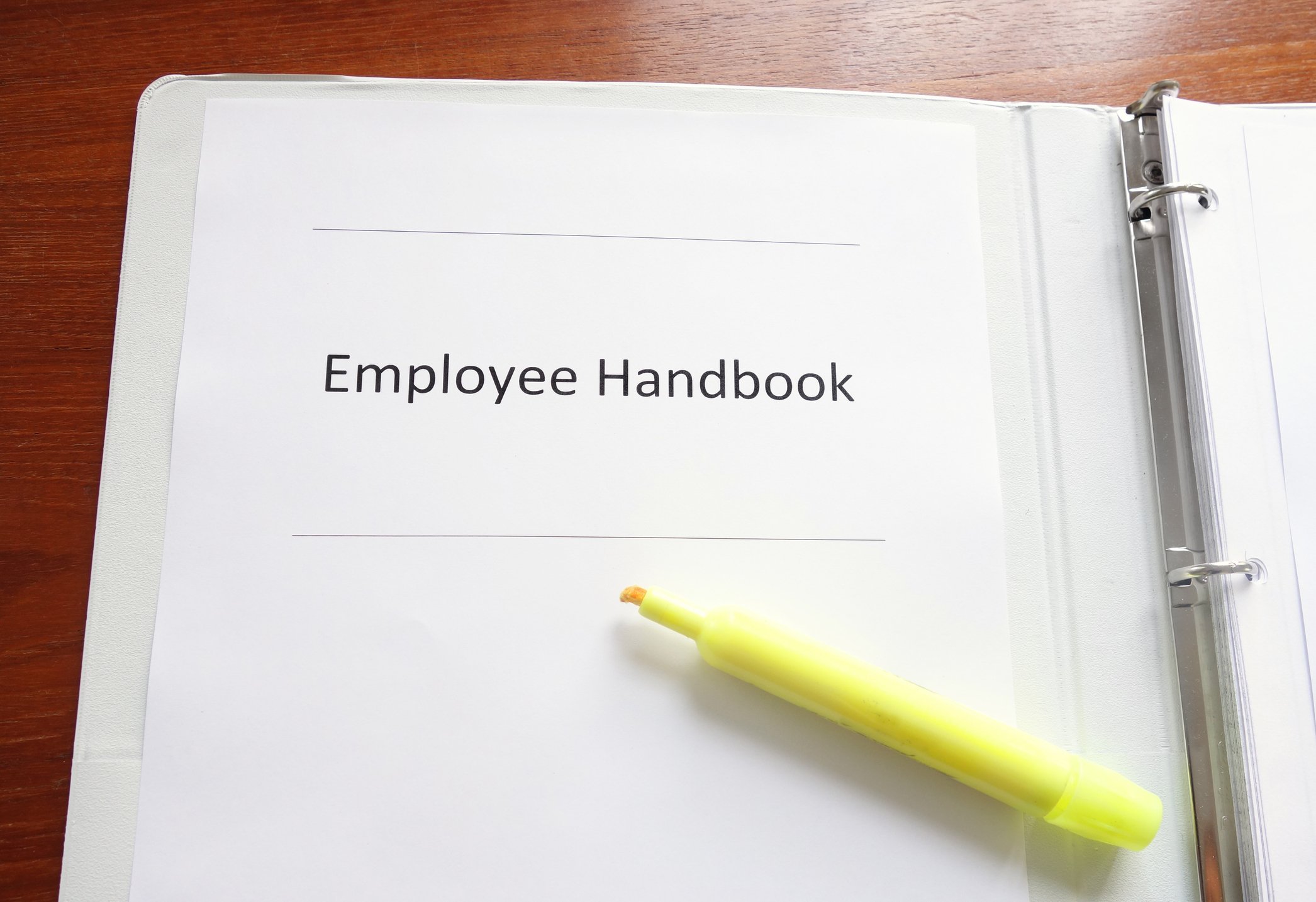 Yellow highlighter resting on employee handbook