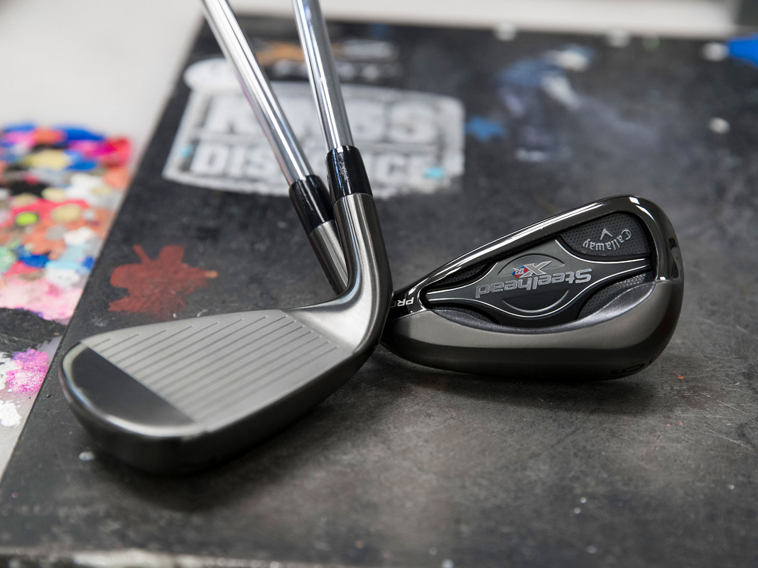 Two golf clubs, one clearly showing the Callaway logo, on a black surface.