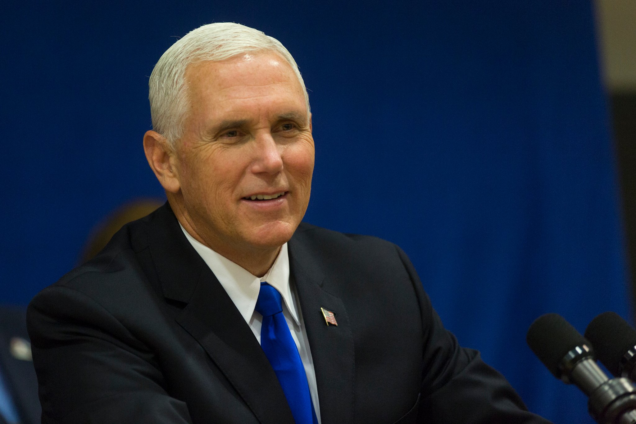 Vice President Mike Pence sitting behind a microphone and fielding questions.