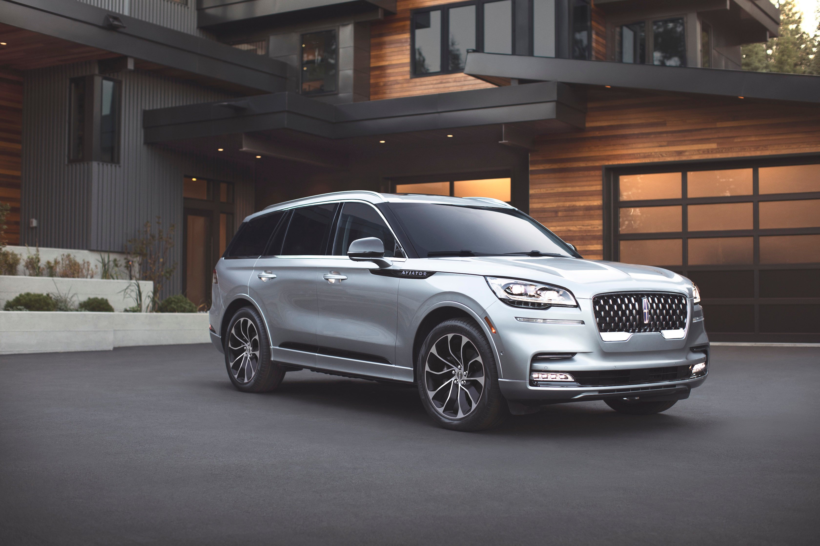 A silver 2019 Lincoln Aviator Grand Touring, parked in front of an upscale home. Surprisingly for a modern SUV, the softly-curved Aviator does not look large or imposing.