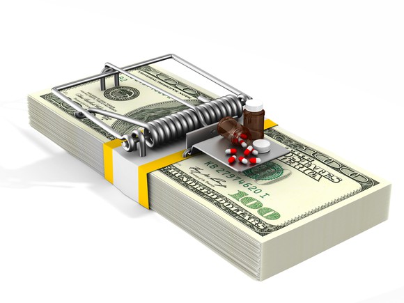 Medicine used as bait on a mouse trap made from a stack of cash.