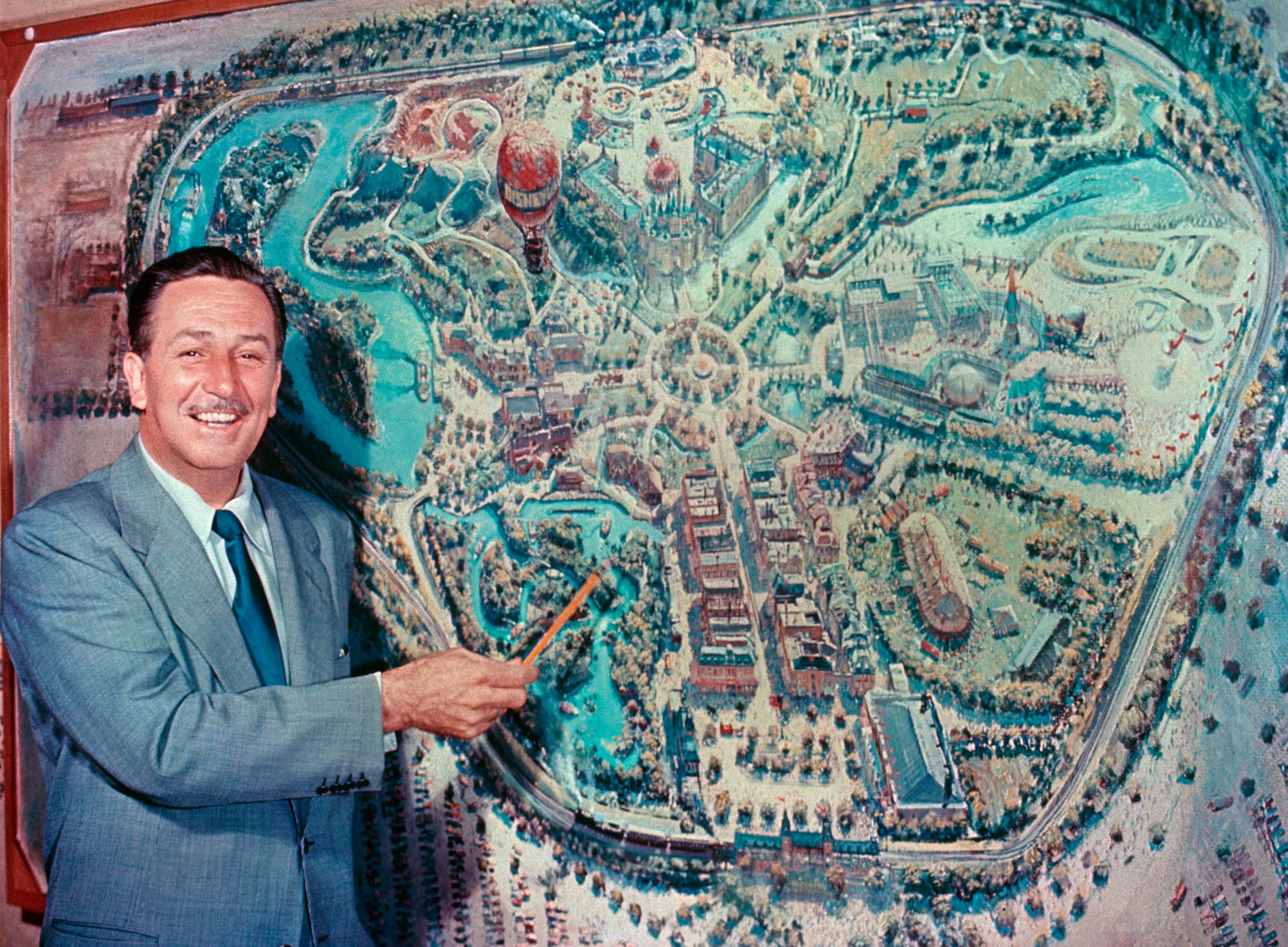 Walt Disney pointing to park plans. 