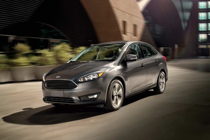 A gray Ford Focus in front of a building