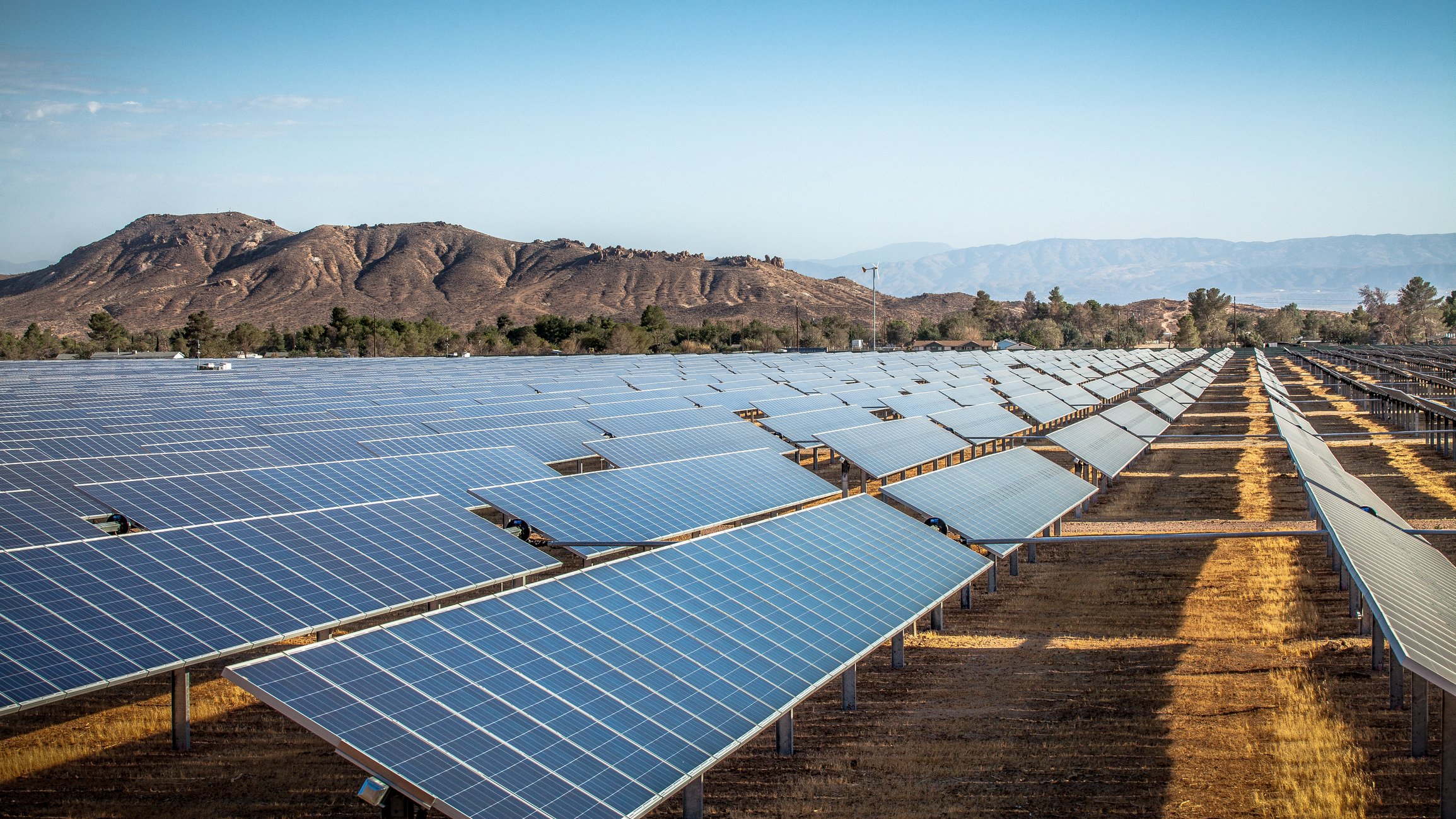 Solar farm in the desert with mountains in the background. 