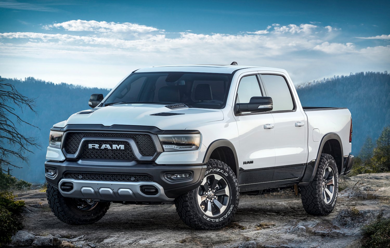 A white 2019 Ram 1500 Rebel, shown parked on a mountain road.