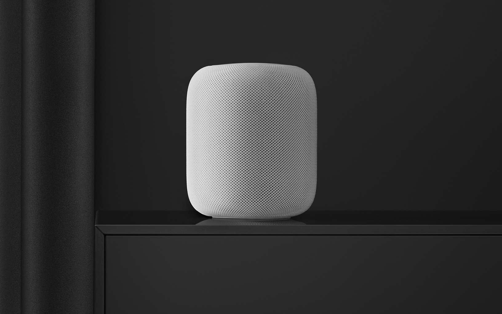 White HomePod on a black shelf