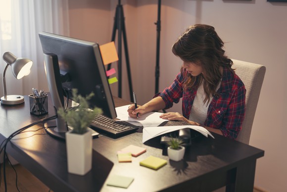 Woman writing notes at desk.