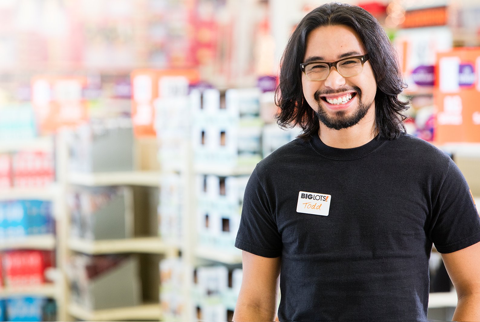 A Big Lots employee smiles with merchandise in the backgorund