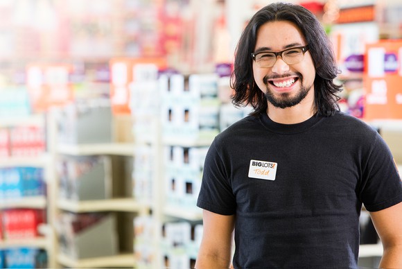 A Big Lots employee smiles with merchandise in the backgorund