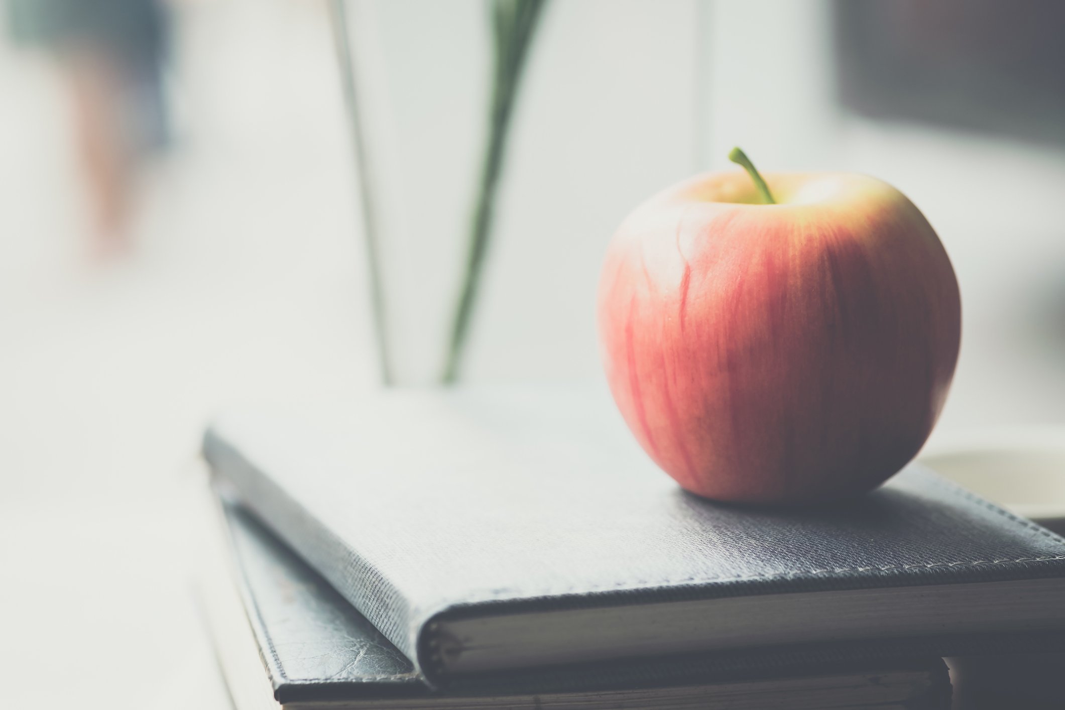 A red apple resting on a stack of books.