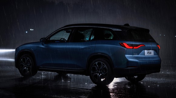 A blue NIO ES8 shown driving in heavy rain at night. 