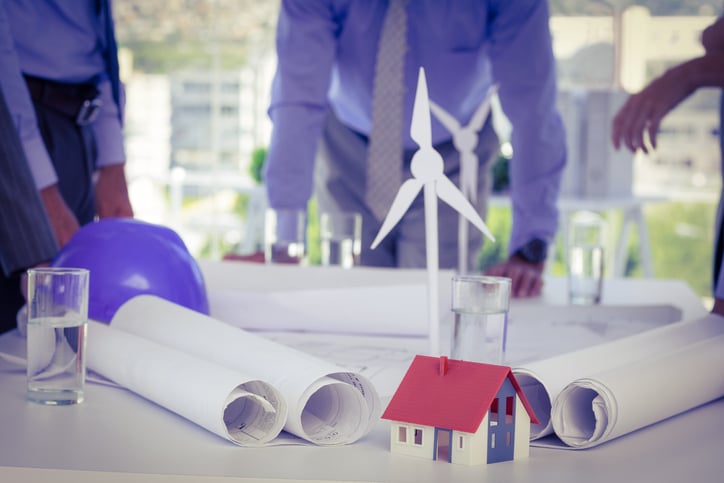 Paper windmills as part of a scale-down prototype. People stand around the presentation table in the background.