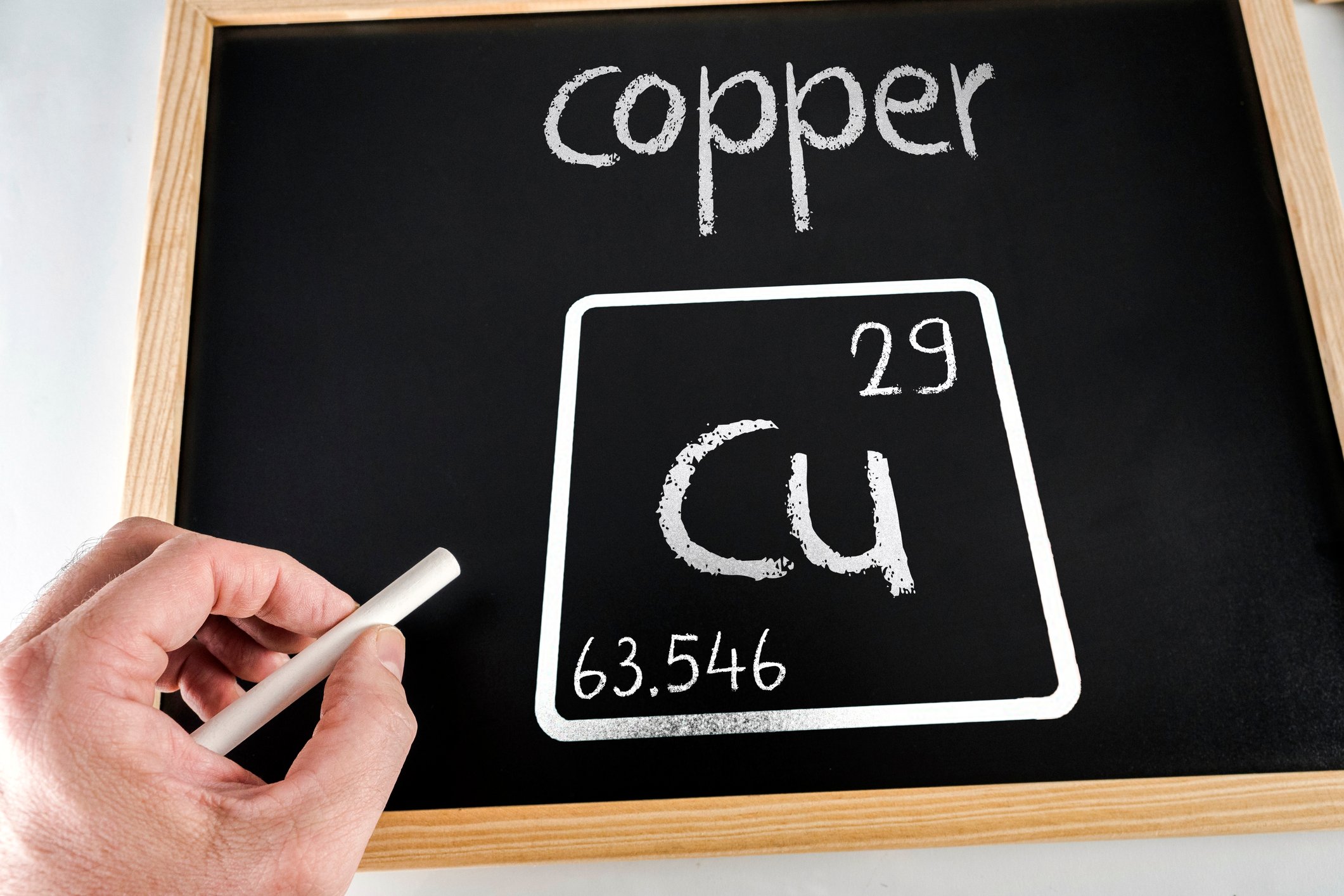 The chemical symbol for copper is drawn in chalk on a blackboard.