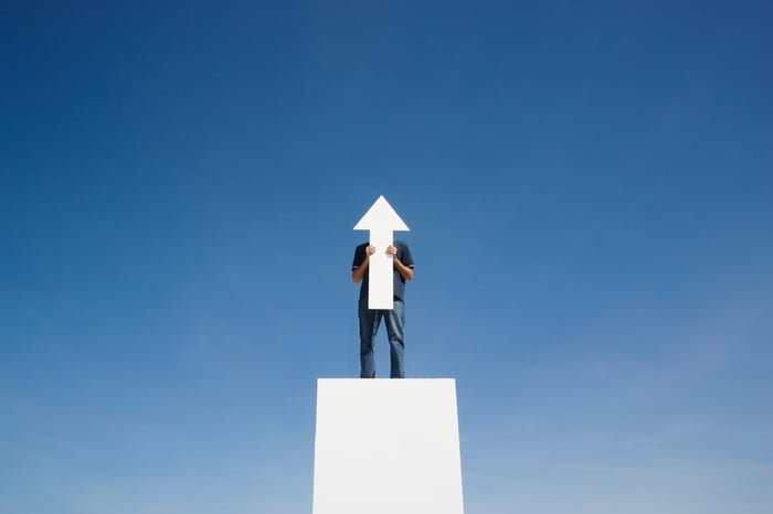 A man holding an arrow cut out pointing up.