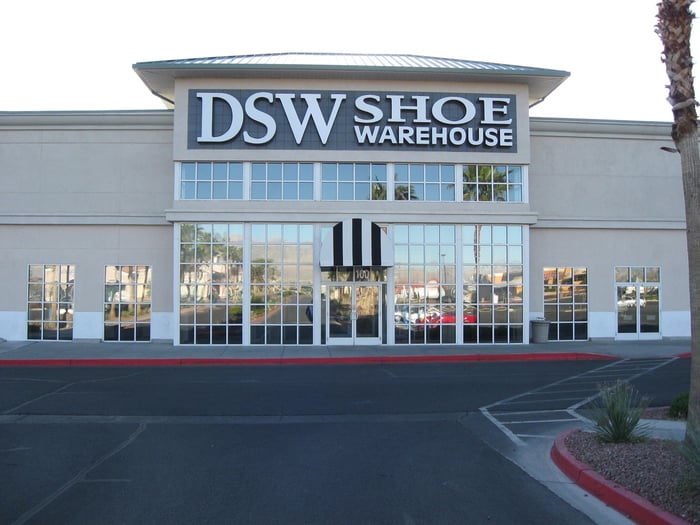 DSW Shoe Warehouse storefront as seen from parking lot, with red curbs and black asphalt.