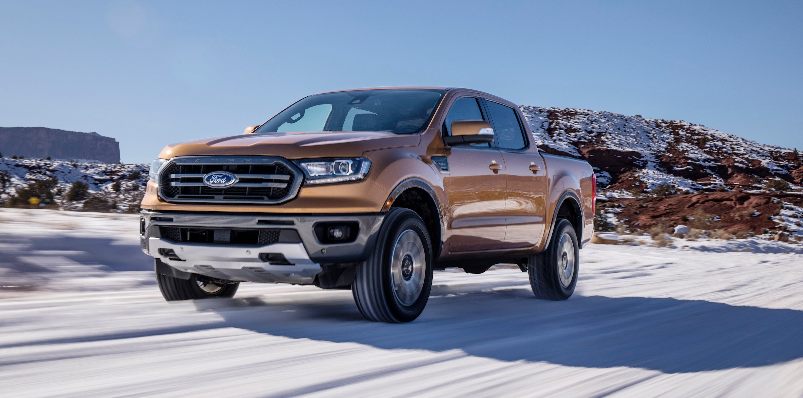 An orange 2019 Ford Ranger, a midsize pickup, on a snowy road.