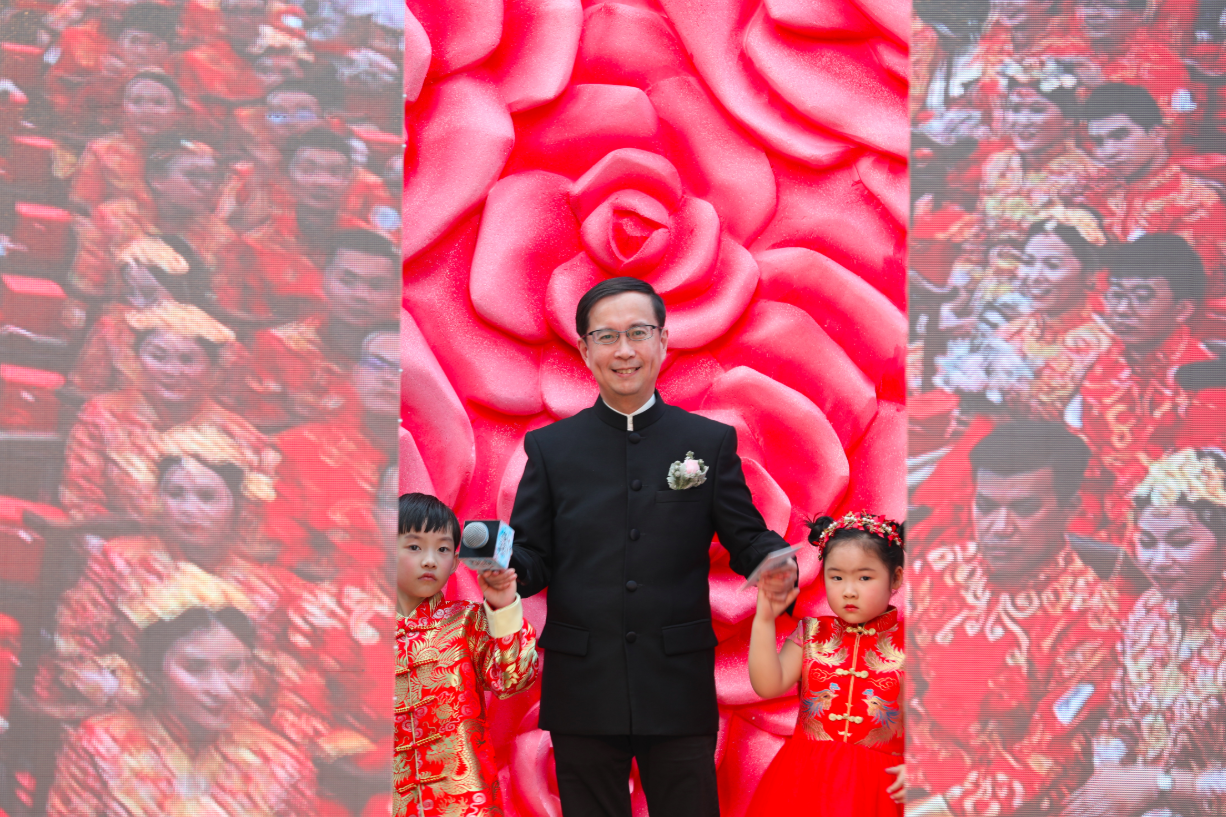 Alibaba CEO Daniel Zhang stands on stage with two young performers during an Alibaba event.