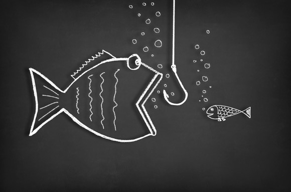 A small fish looks on as a bigger fish with an open mouth moves toward a hook on a line.