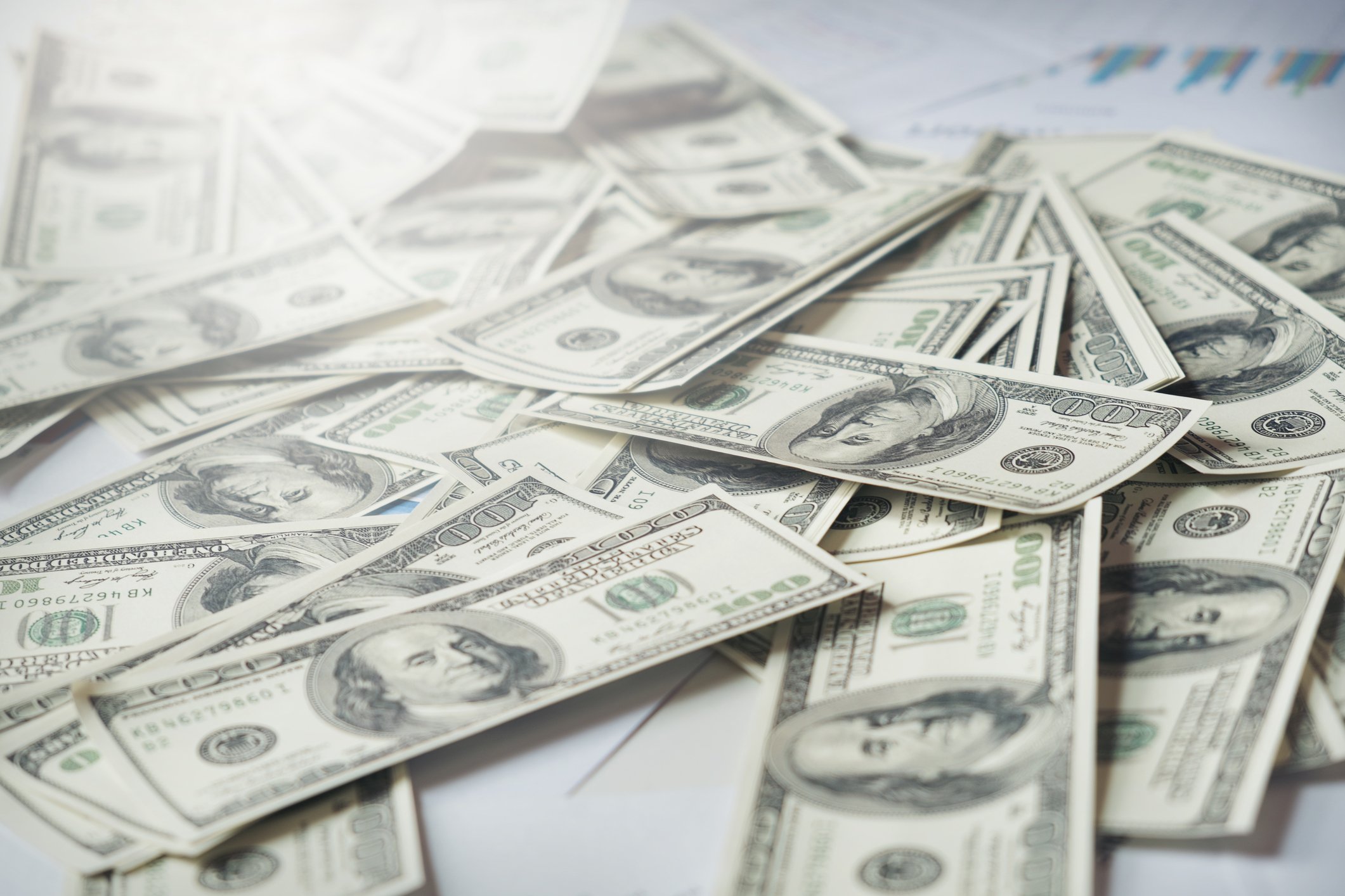 One hundred dollar bills spread out on a flat surface.