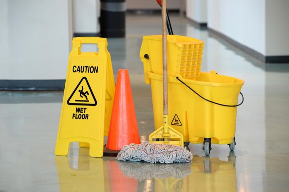 Mop and bucket beside a sign reading "Caution, wet floor."
