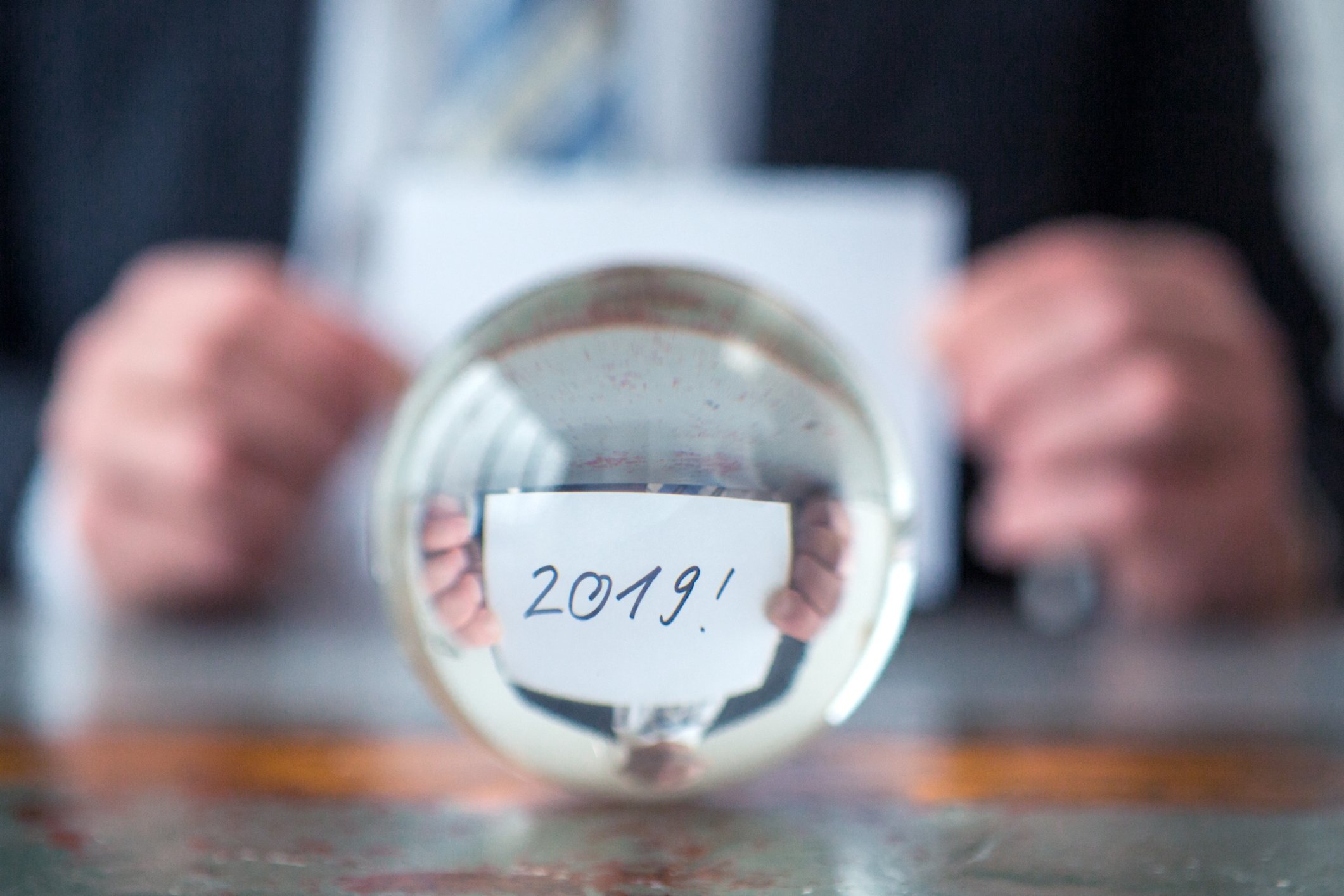 Man holding card with 2019 written on it behind a glass ball.