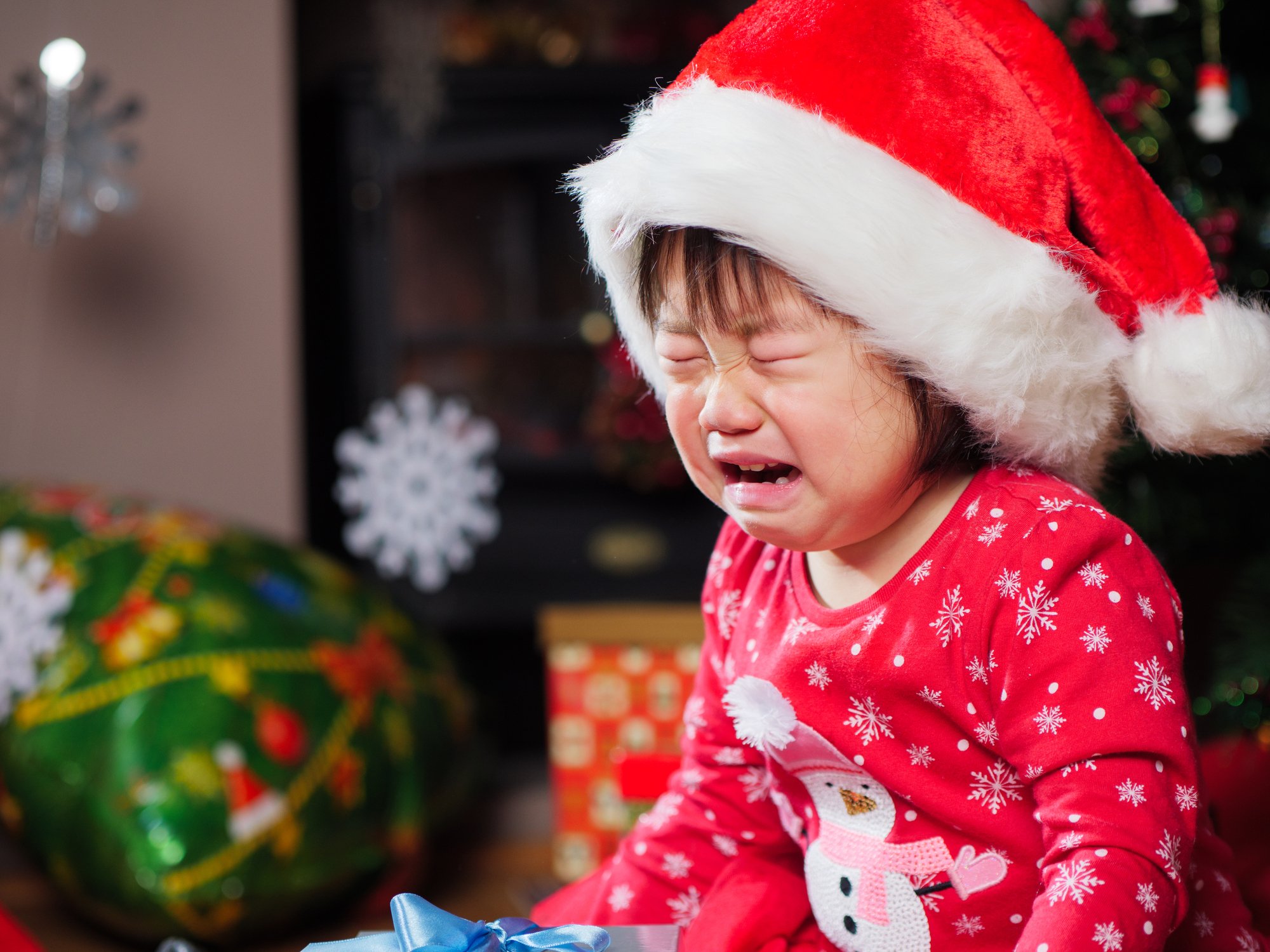 Child wear Santa hat crying
