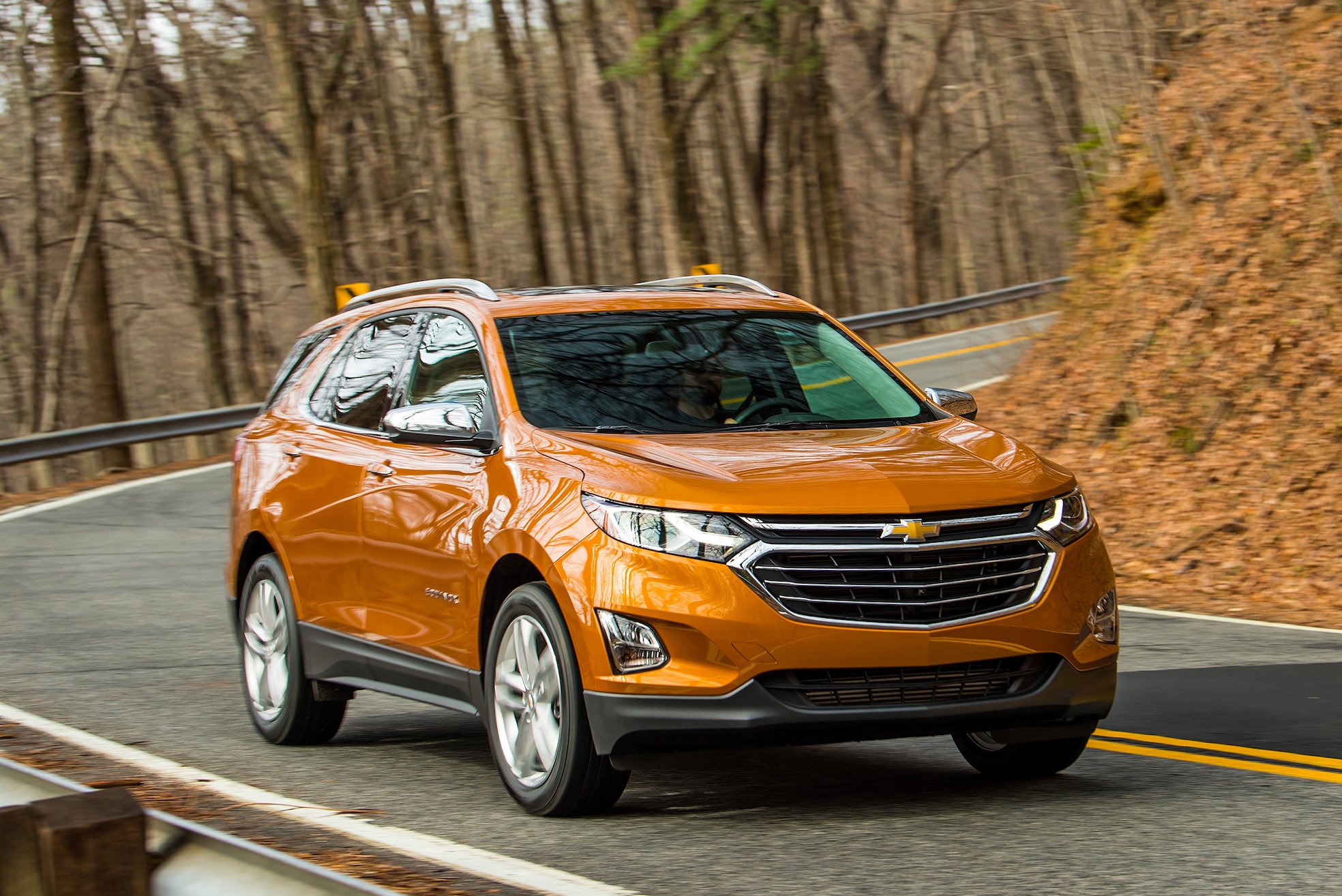 An orange Chevrolet Equinox, a compact crossover SUV, on a mountain road.