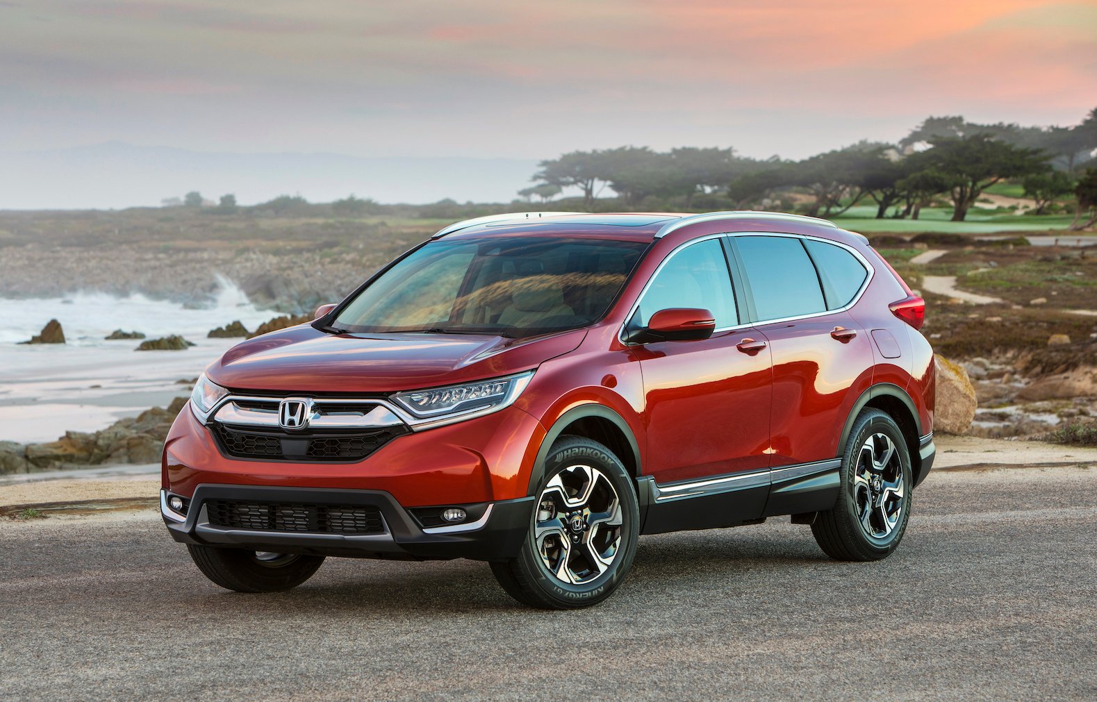 A red Honda CR-V, a compact crossover SUV, parked on a beach road.