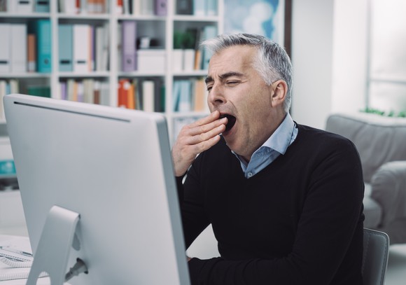 Man holding hand over his mouth while yawning.
