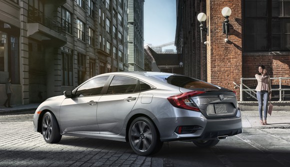 A silver Honda Civic, a compact sedan, on a city street.