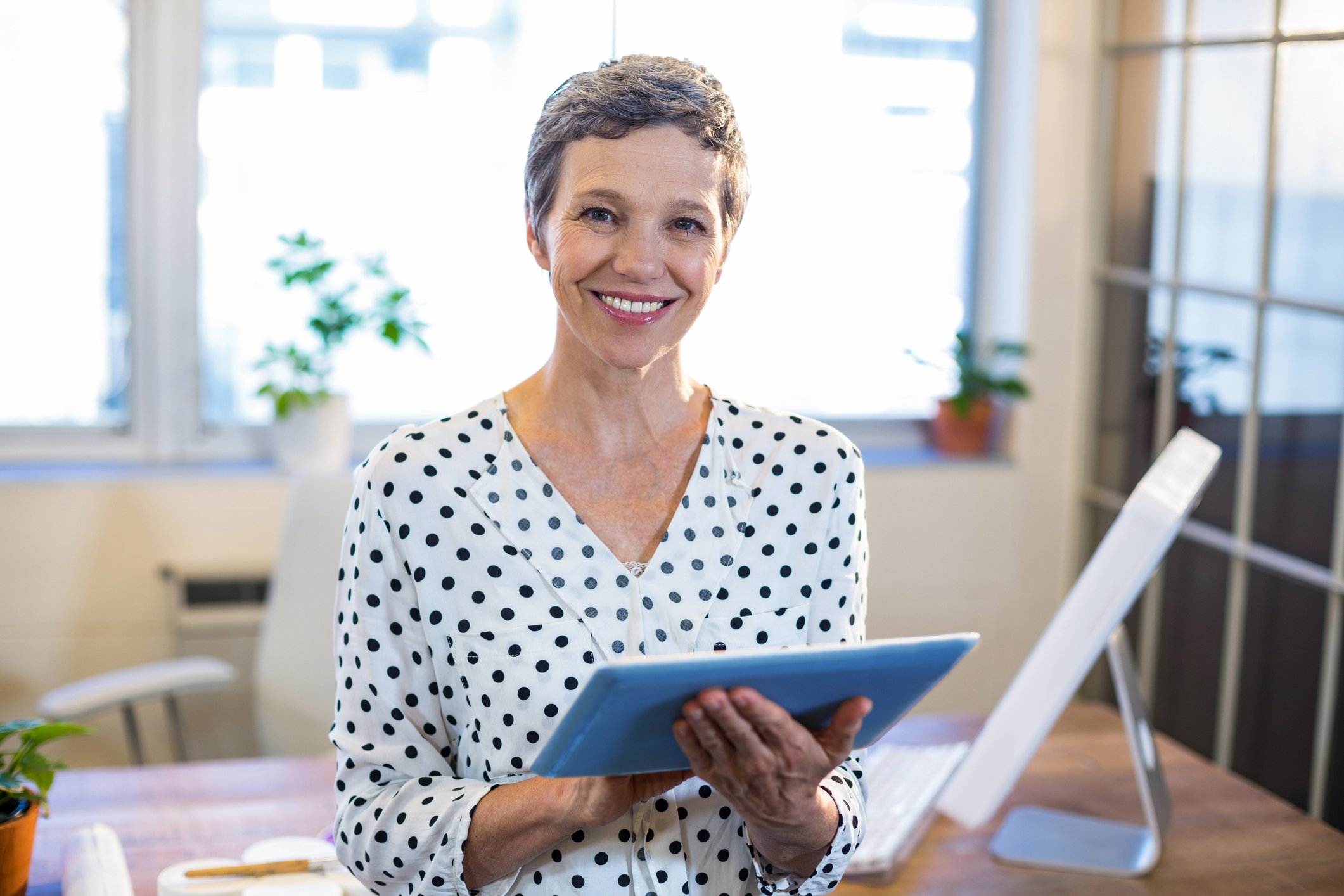 Older woman smiling and holding tablet
