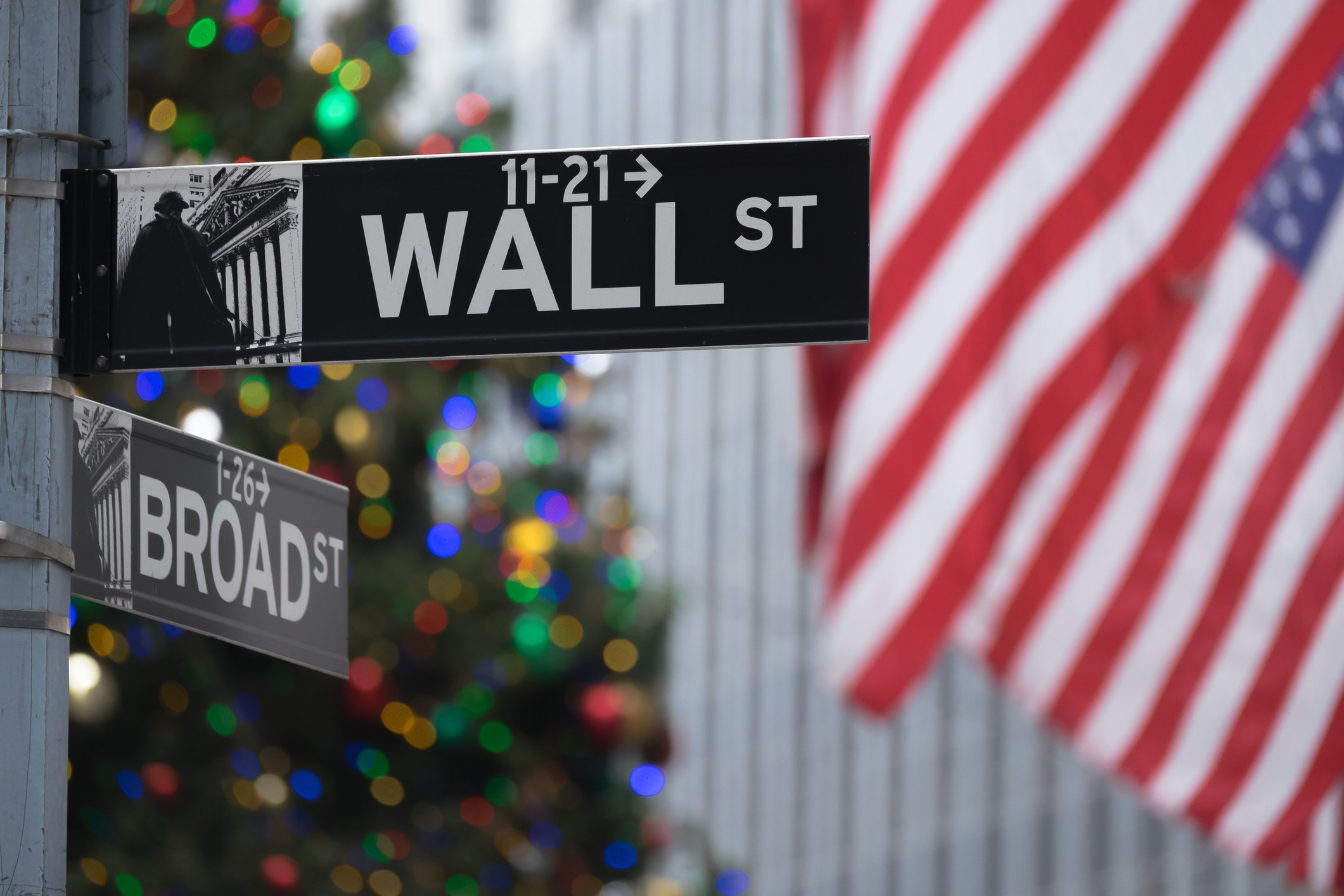 Wall Street and Broad Street signs with American flags and a Christmas tree in the background