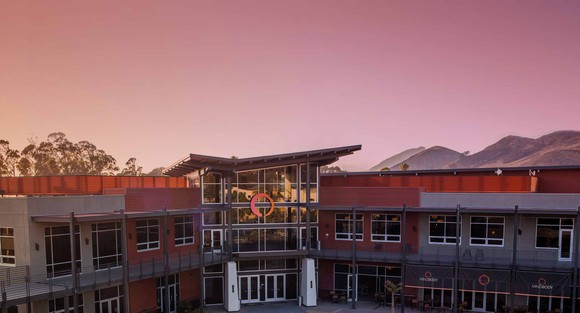 Orange and gray two-story building near dawn with Mindbody logos and signage.