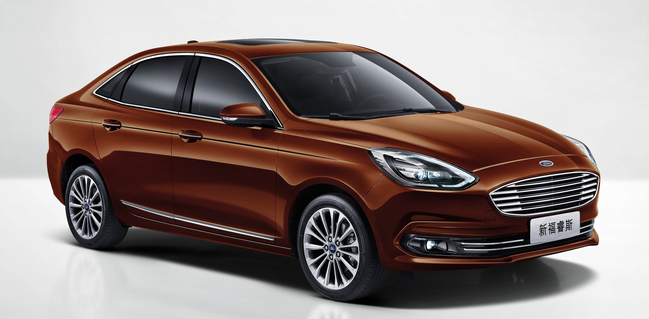 A 2019 Ford Escort, a brown compact sedan, with Chinese-language license plates. 