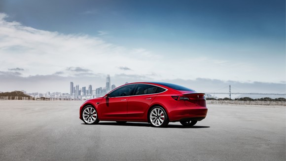 Red Model 3 with a city skyline in the background